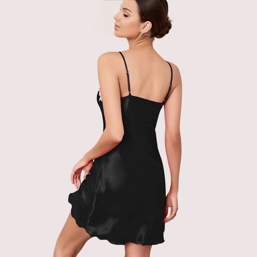 Woman wearing a black satin slip dress on a light pink background