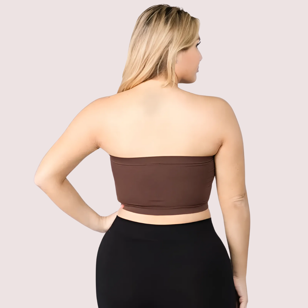 Woman wearing a brown strapless top and black pants on a light pink background