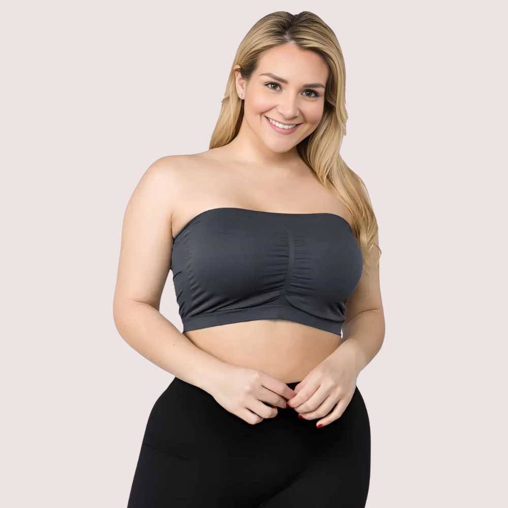 Woman wearing a black strapless top and black pants on a light pink background
