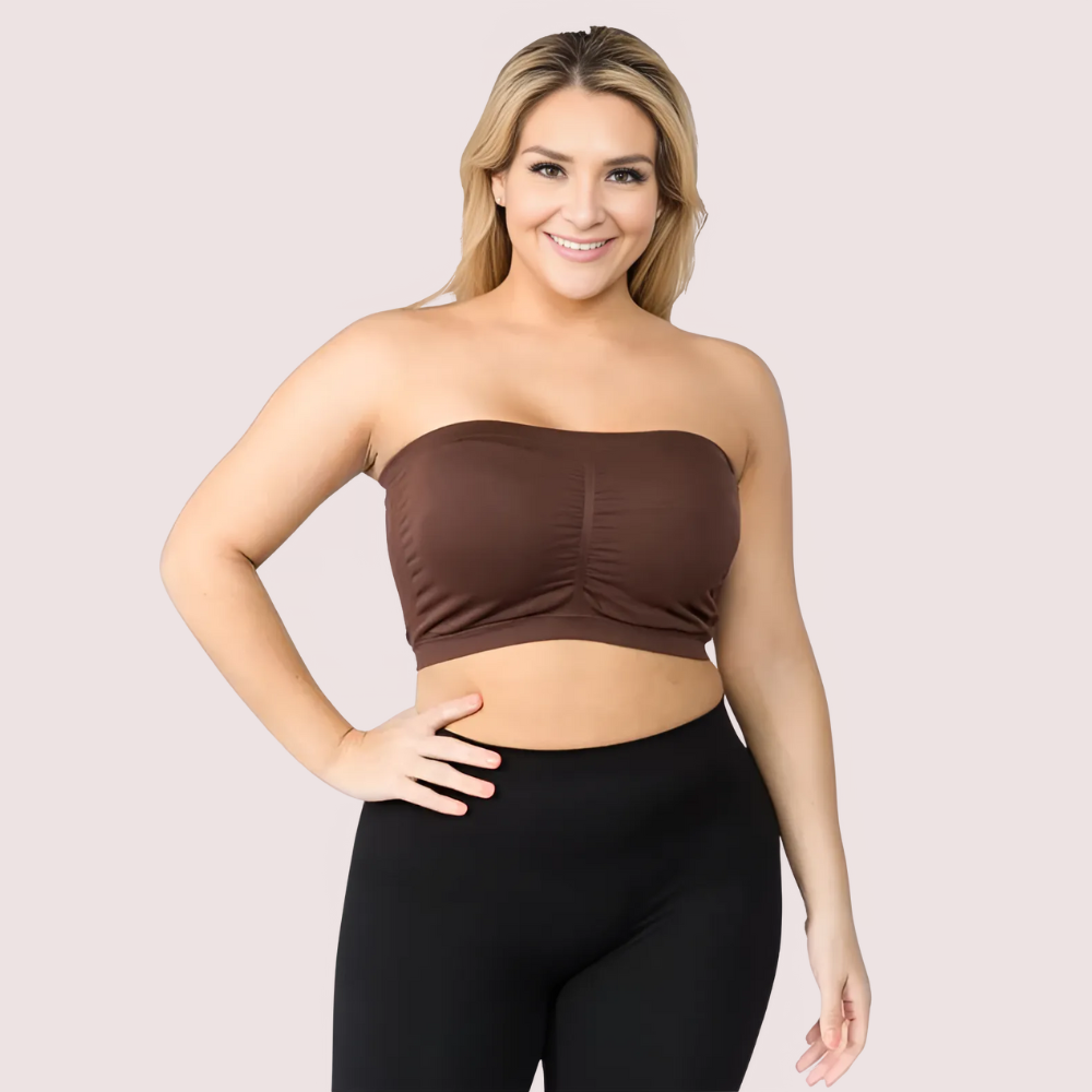 Woman wearing a brown strapless top and black leggings on a light pink background