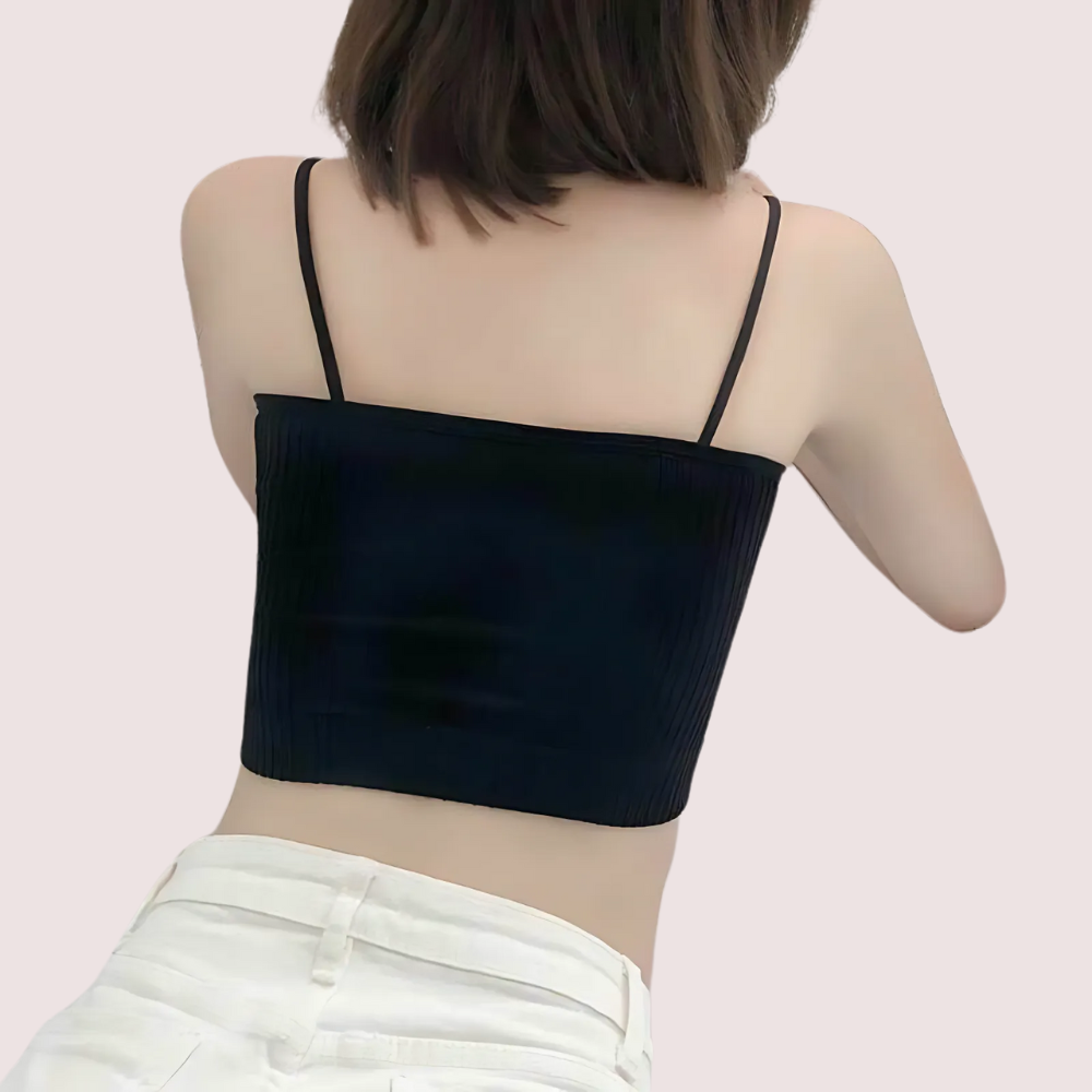 Person wearing a black crop top with thin straps on a light pink background