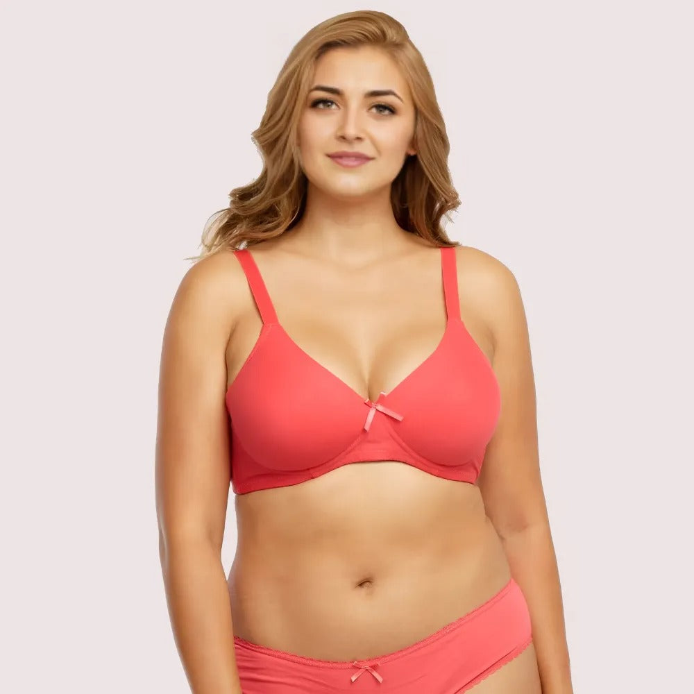 Woman wearing a coral pink bra and panties set on a light pink background