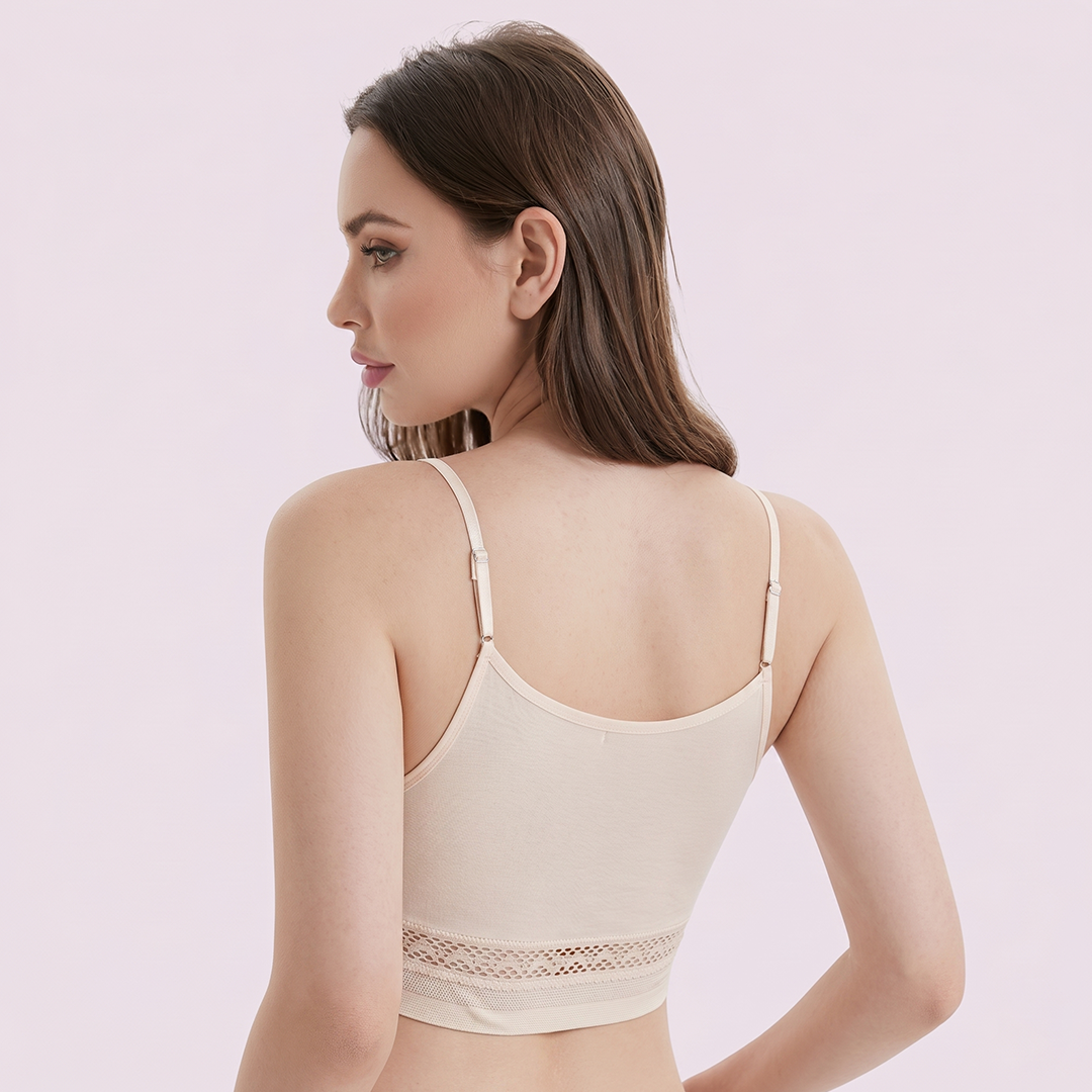 Woman wearing a beige bralette with lace trim on a light pink background
