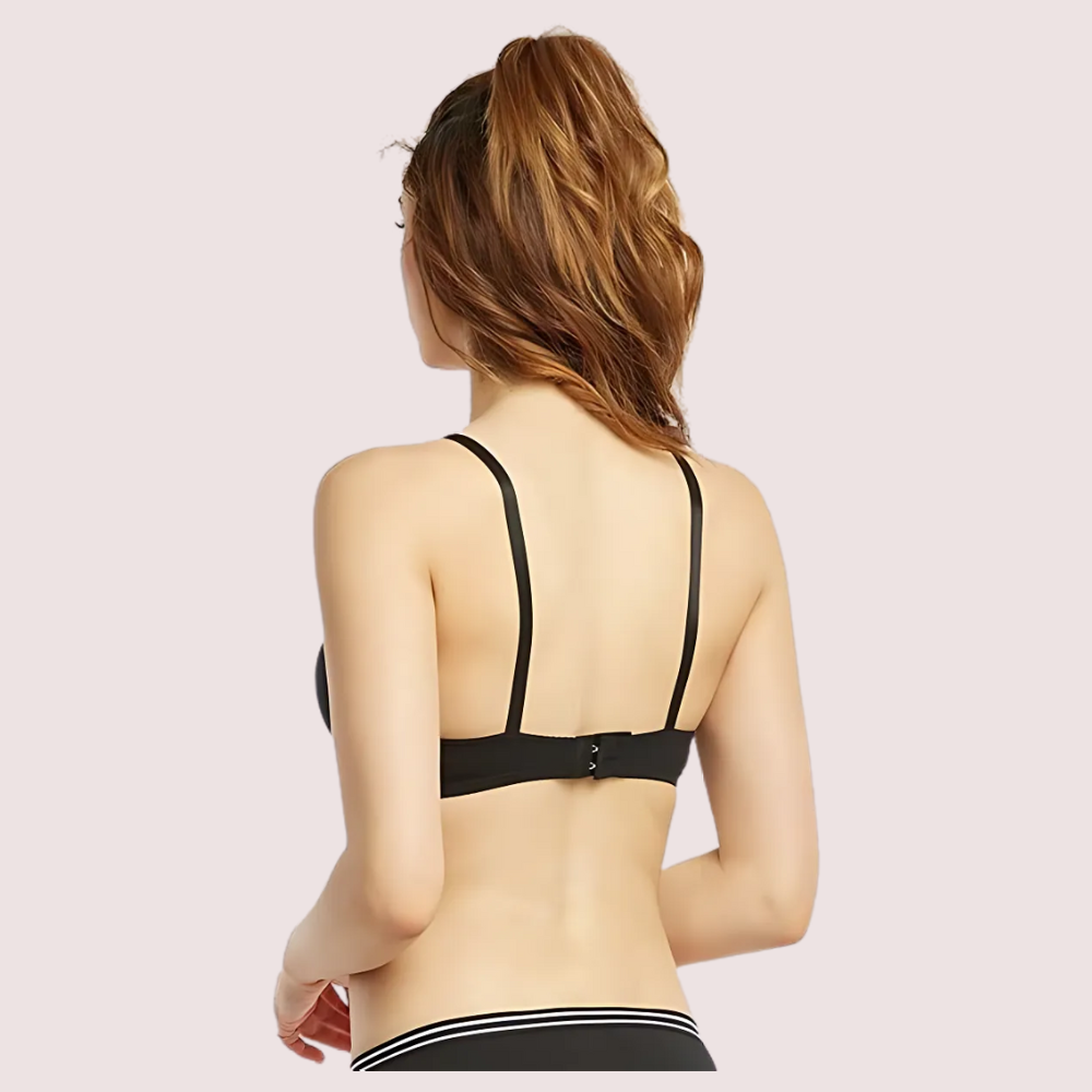 Woman wearing a black bra on a light pink background