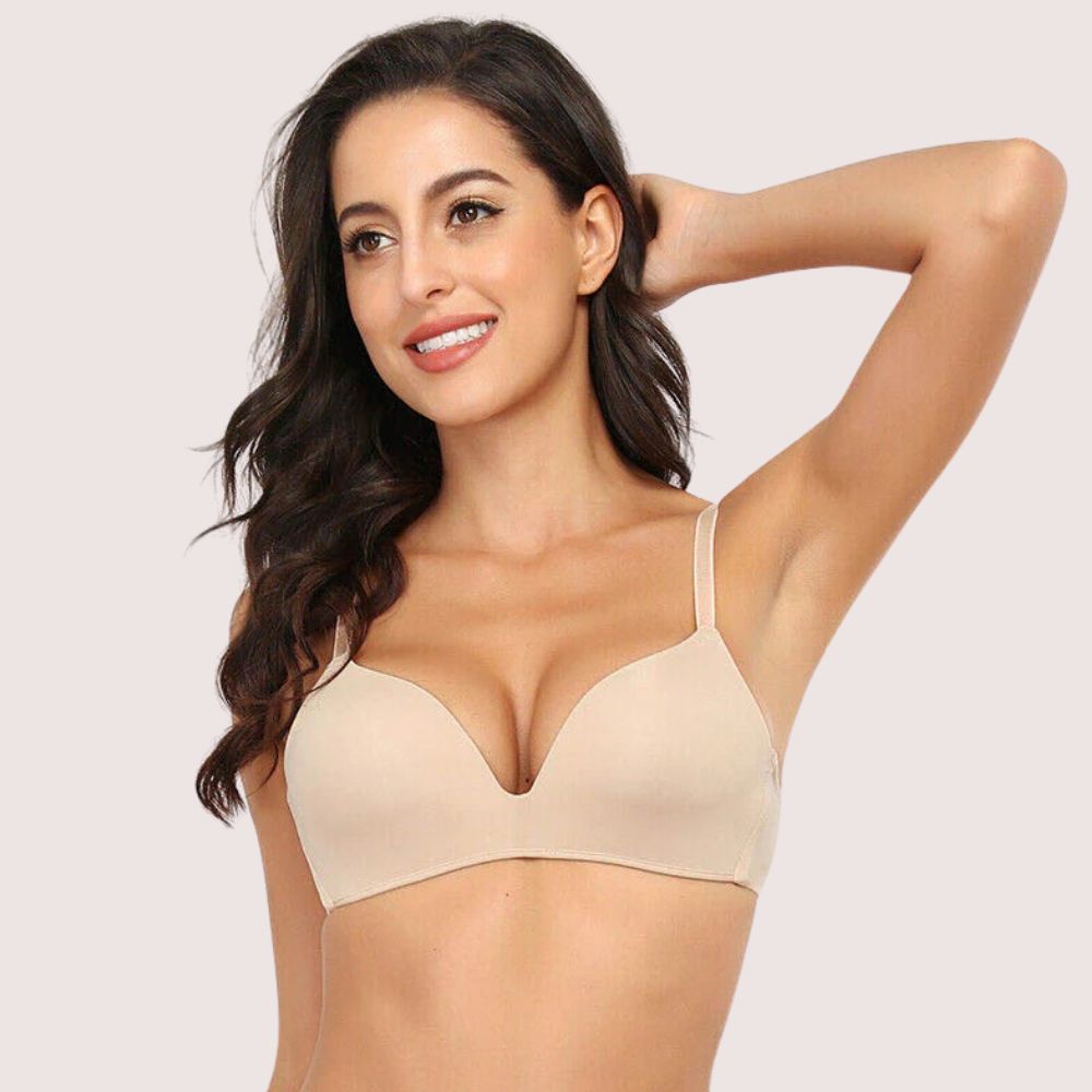 Woman wearing a beige bra against a plain background