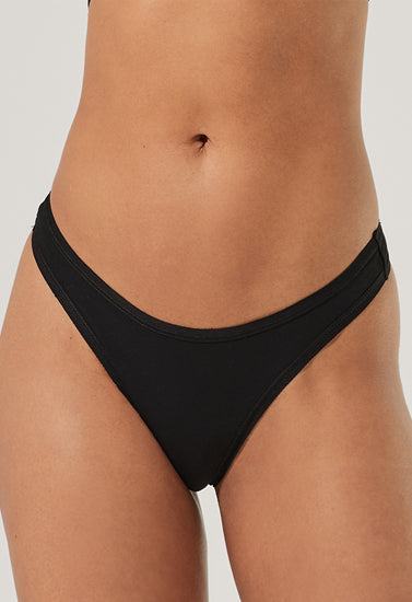 Black bikini bottom worn by a person on a plain background