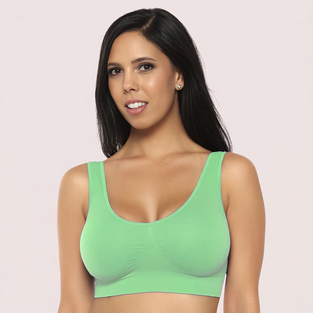 Woman wearing a green sports bra against a light pink background