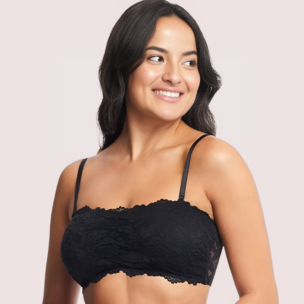 Woman wearing a black lace bralette against a light pink background
