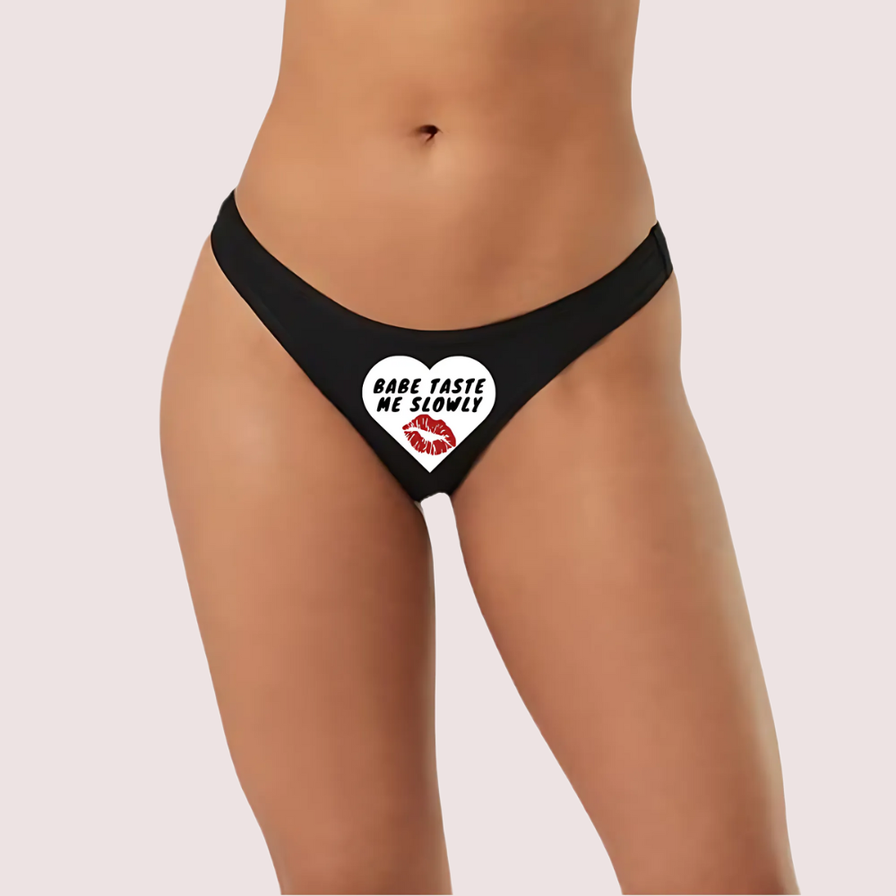 Black thong with a heart design and text on a plain background