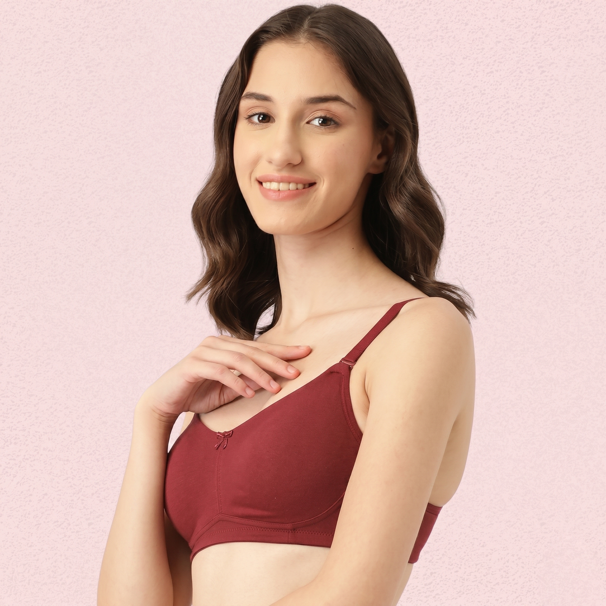 Woman wearing a red bralette against a pink background