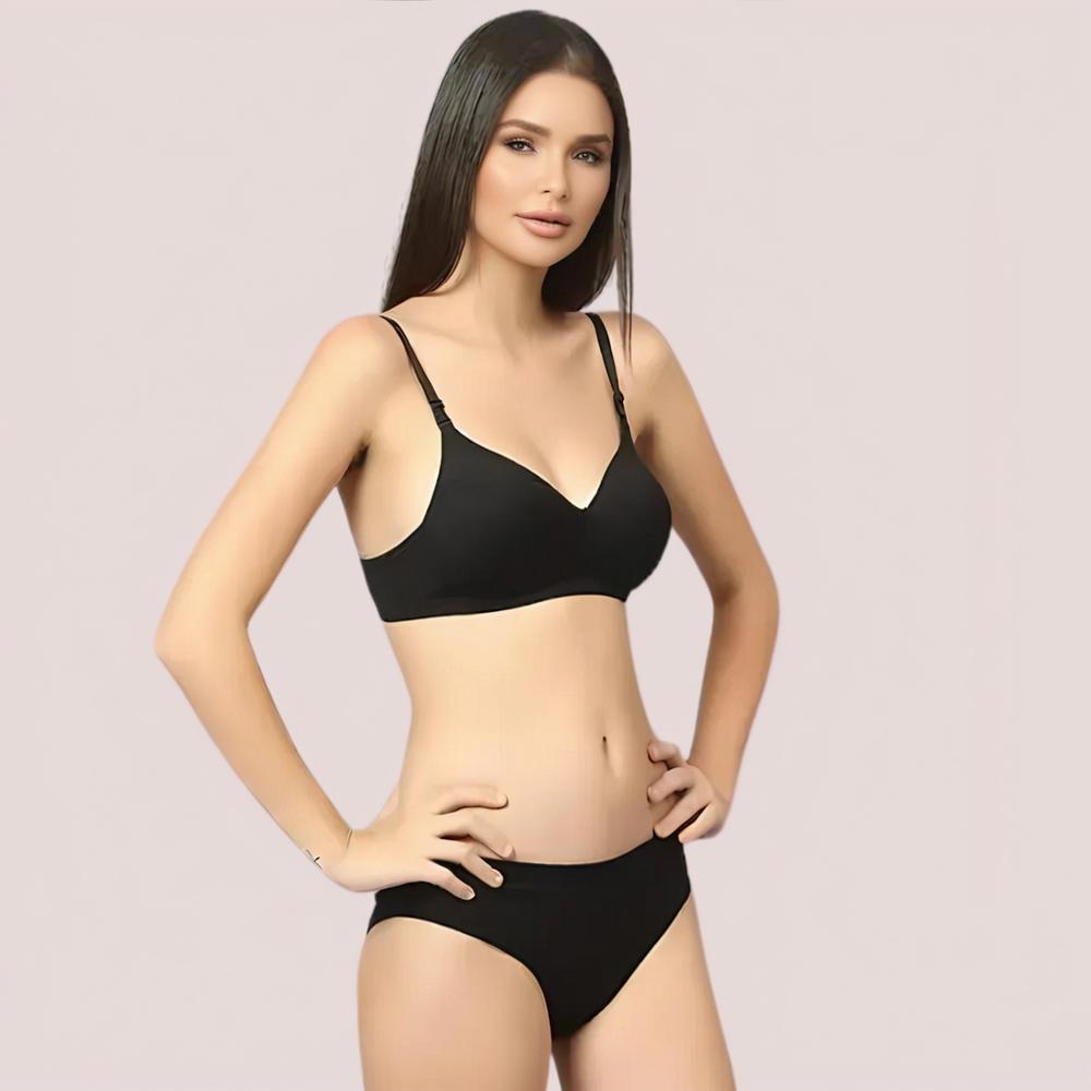 Woman wearing a black bra and panties set on a plain background