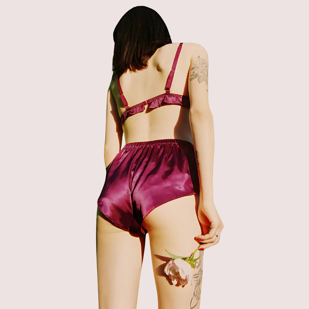 Person wearing a burgundy satin lingerie set on a plain background