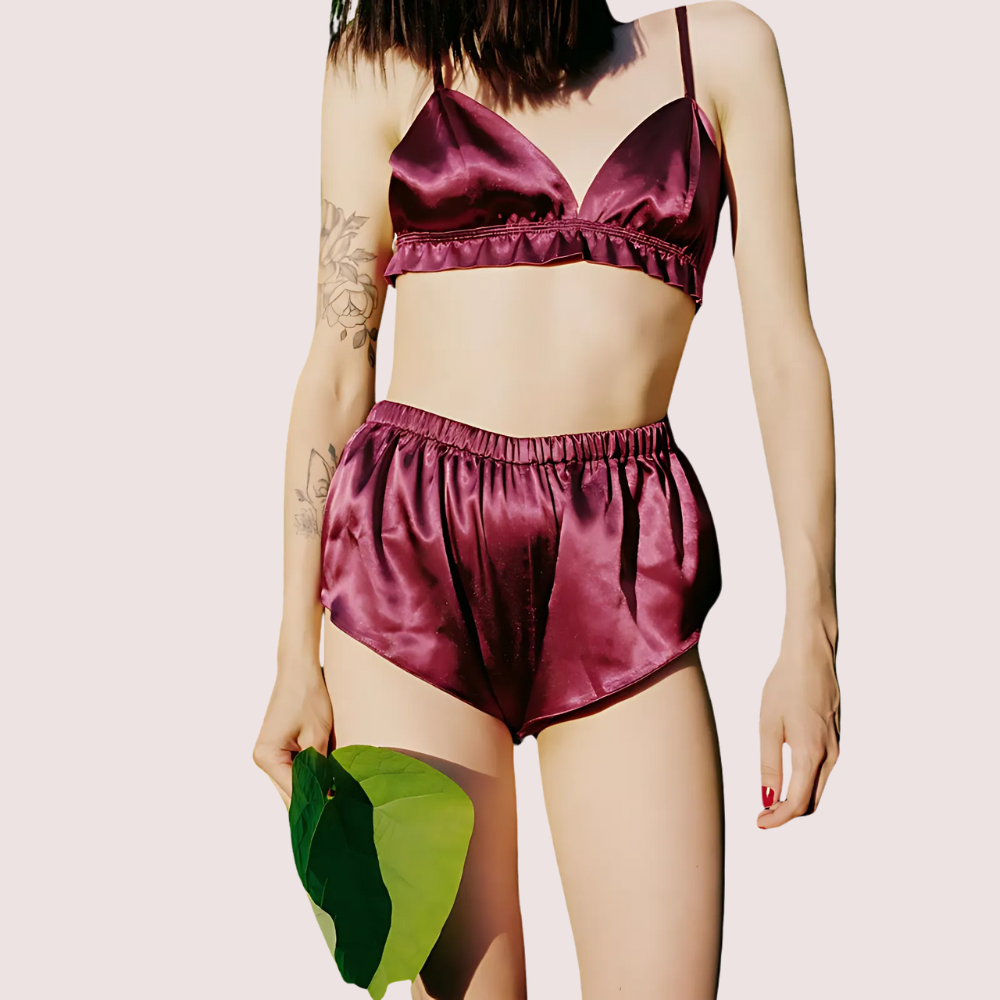 Person wearing a burgundy satin bikini set on a plain background