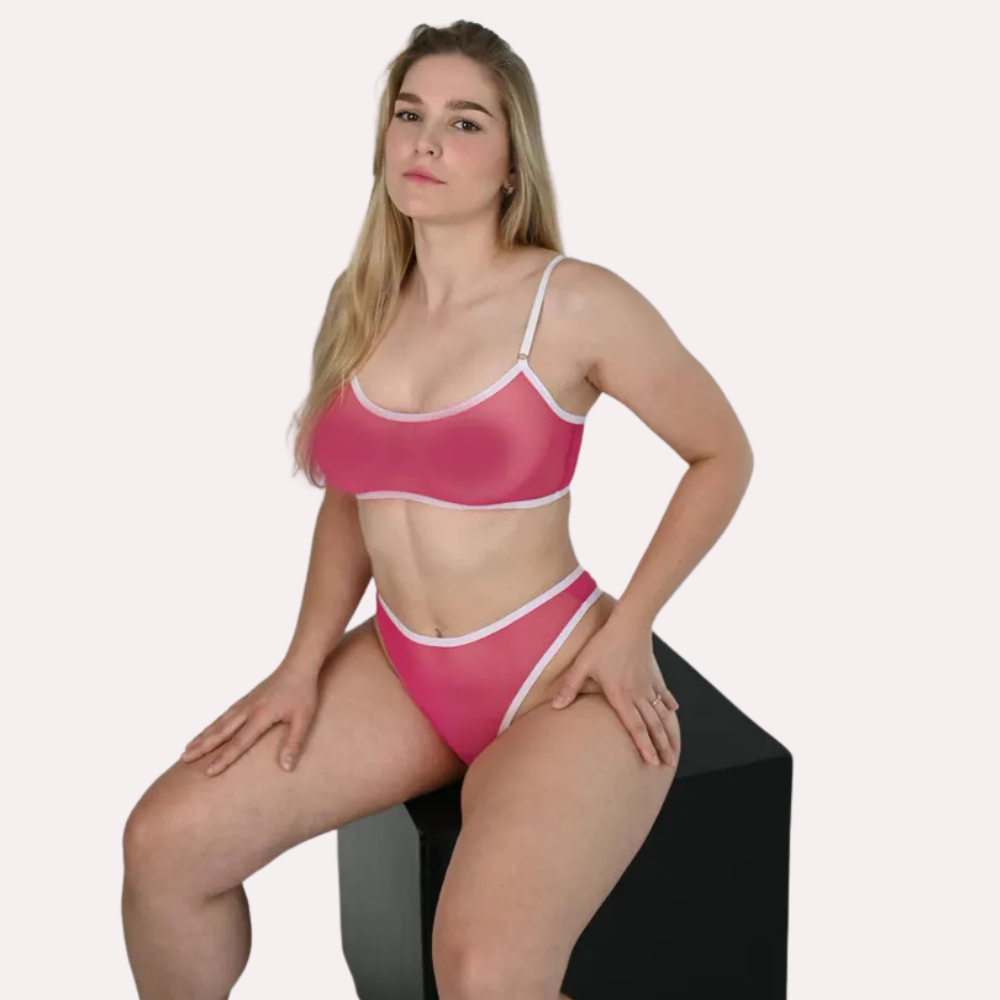 Woman wearing a pink bikini sitting on a black stool against a white background