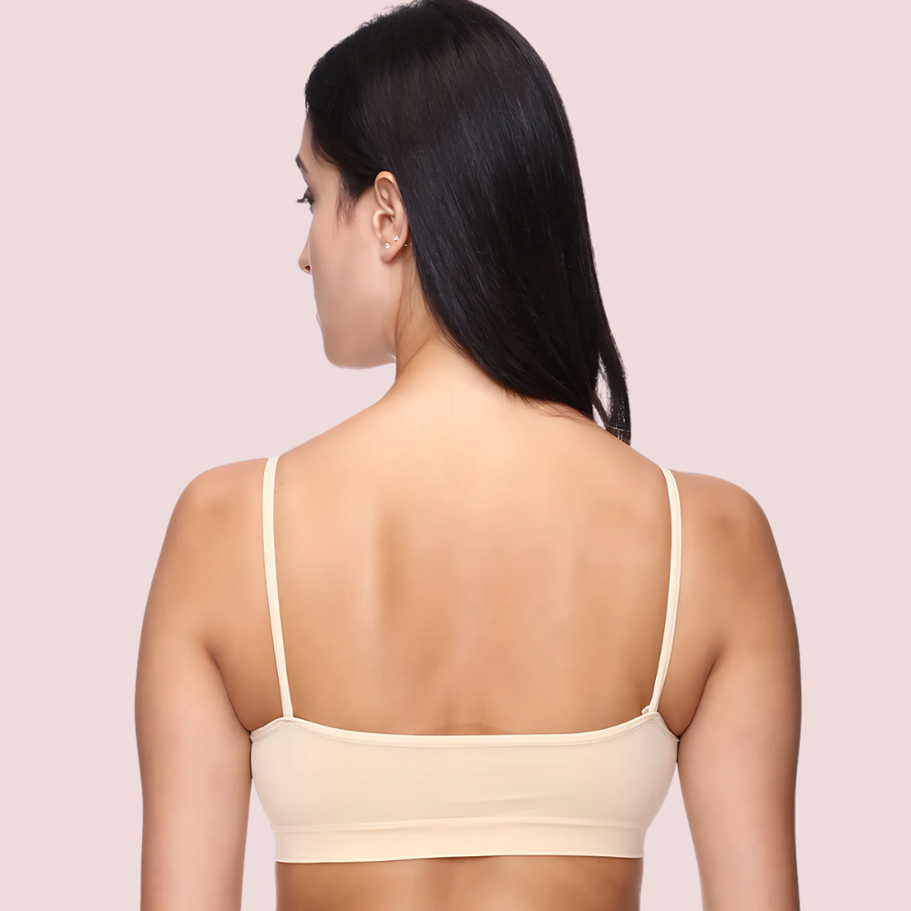Woman wearing a beige bralette against a light pink background