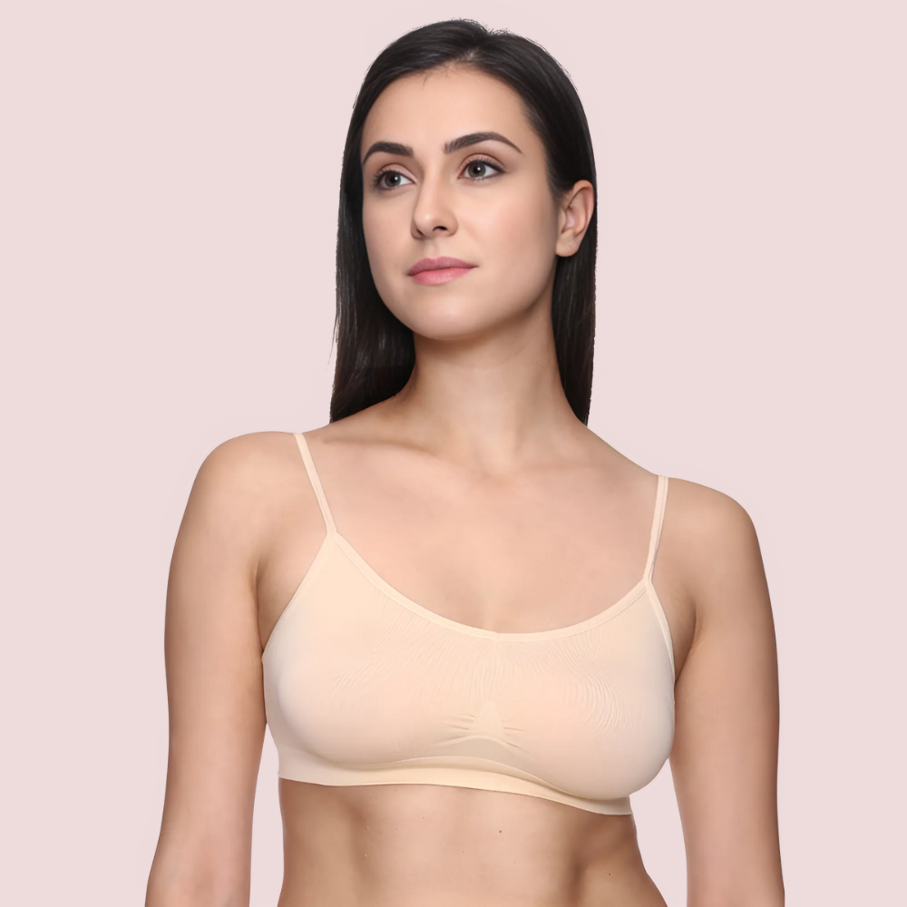 Woman wearing a beige bralette against a light pink background