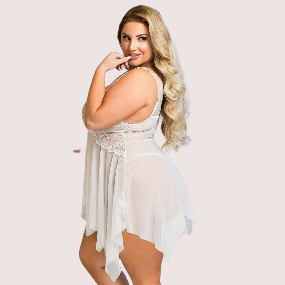 Woman wearing a sheer white dress with lace details on a light pink background