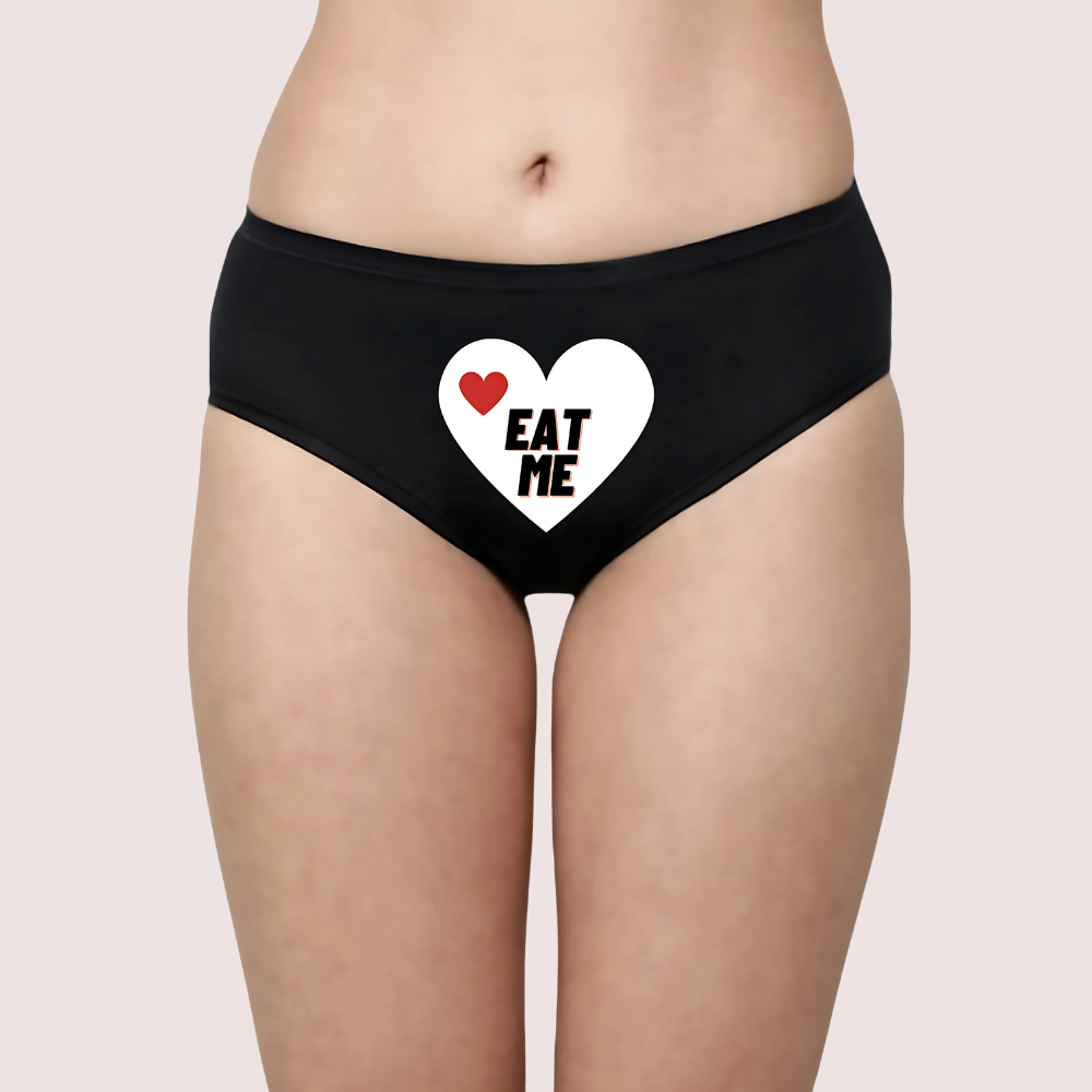 Black underwear with a heart design and 'EAT ME' text on a plain background