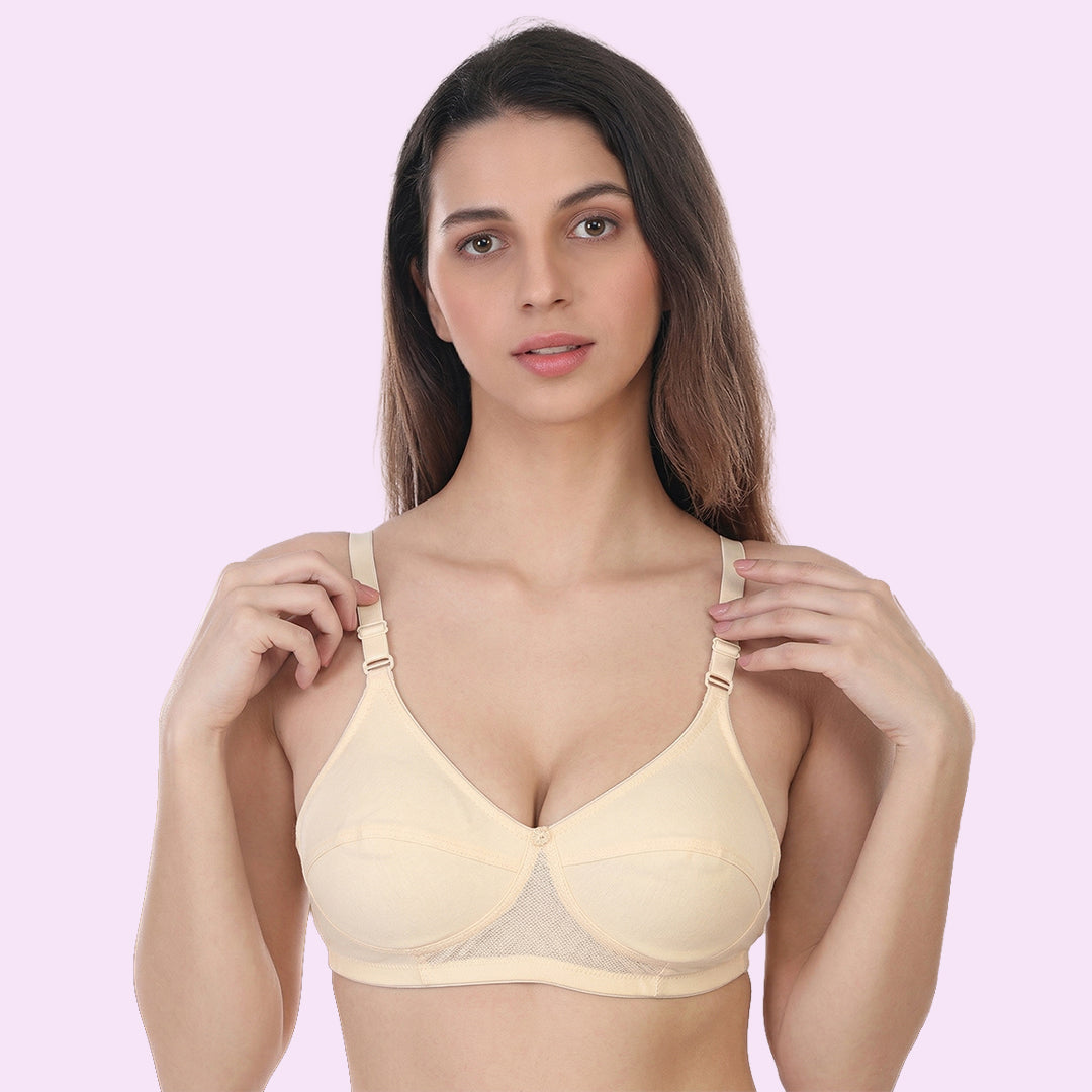 Woman wearing a beige bra against a light pink background