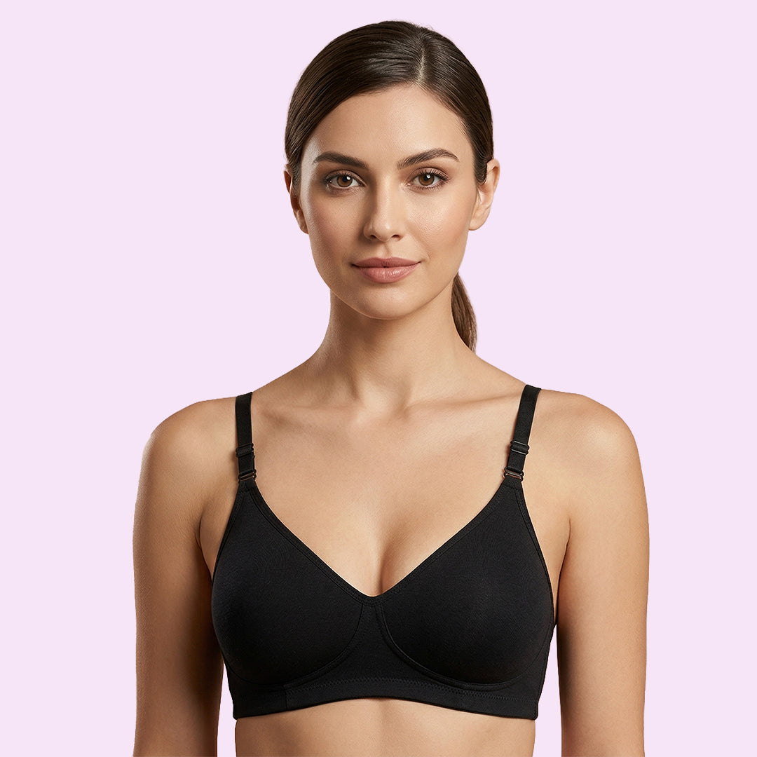 Woman wearing a black bra against a light pink background