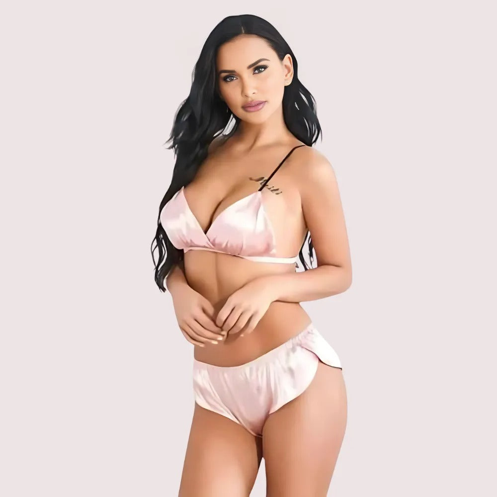 Woman wearing a pink satin lingerie set on a light gray background