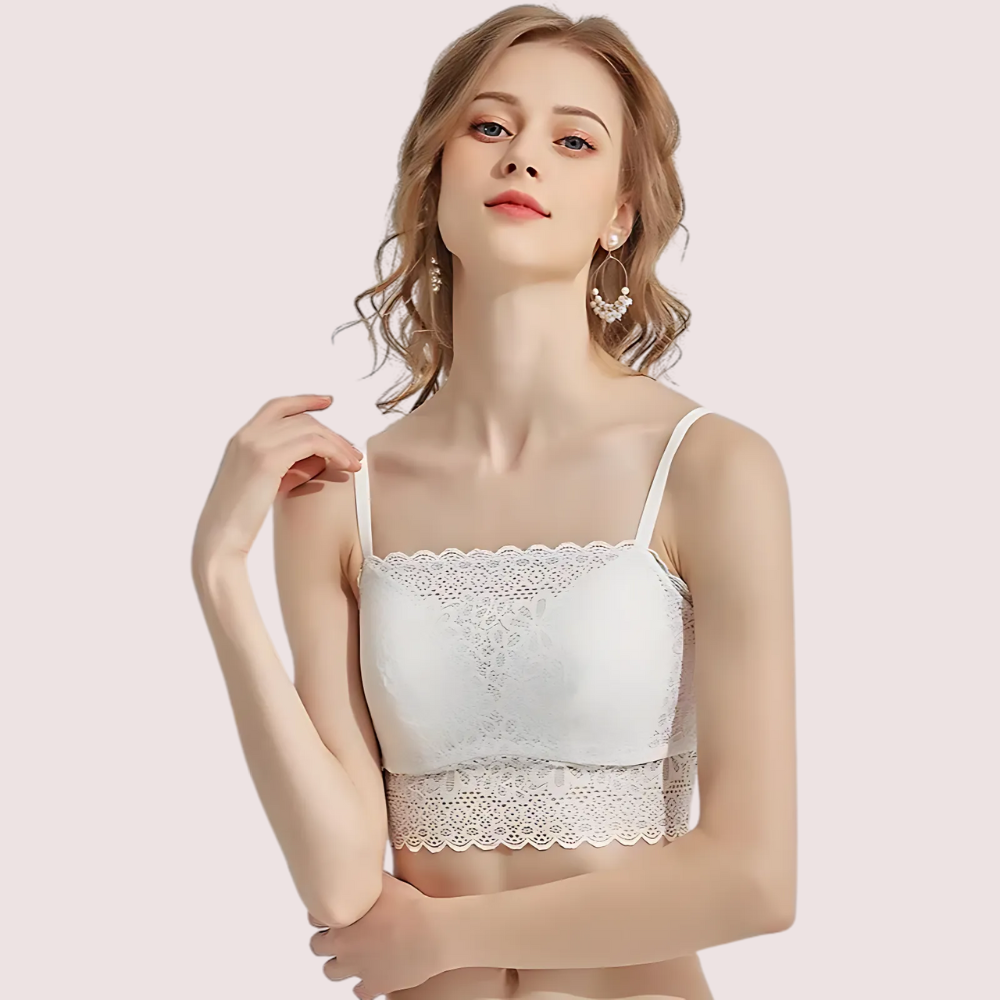 Woman wearing a white lace camisole against a light pink background