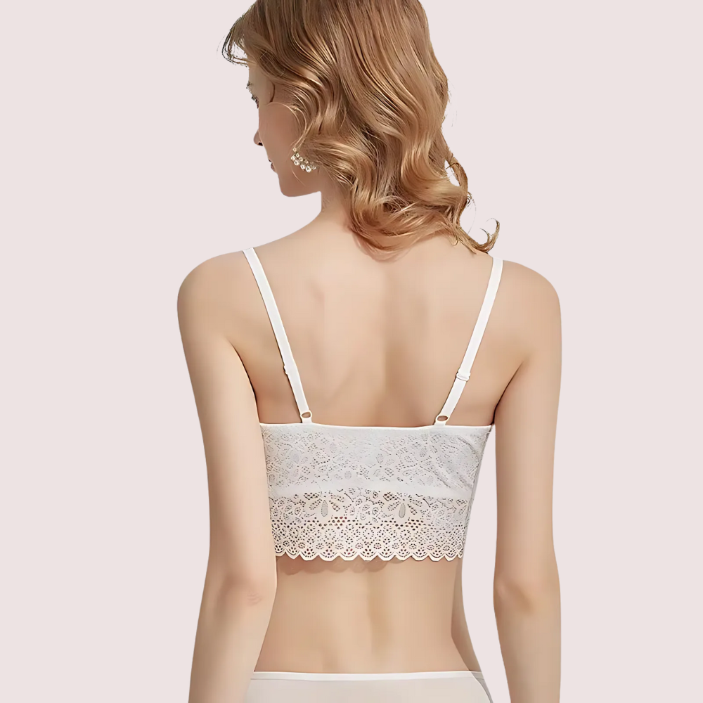 Woman wearing a white lace bralette on a light pink background
