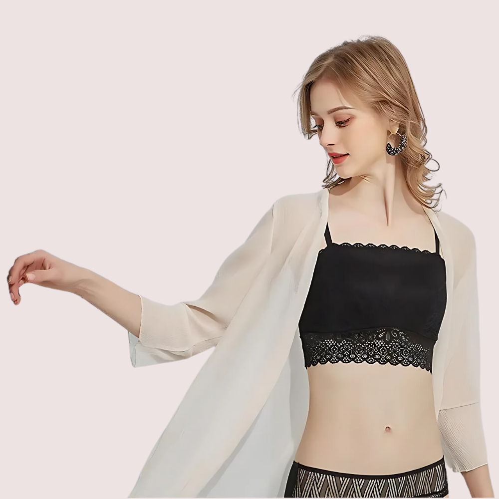 Woman wearing a black lace bralette with a beige cardigan on a light background