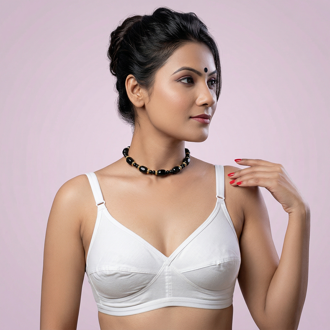 Woman wearing a white bralette against a light pink background