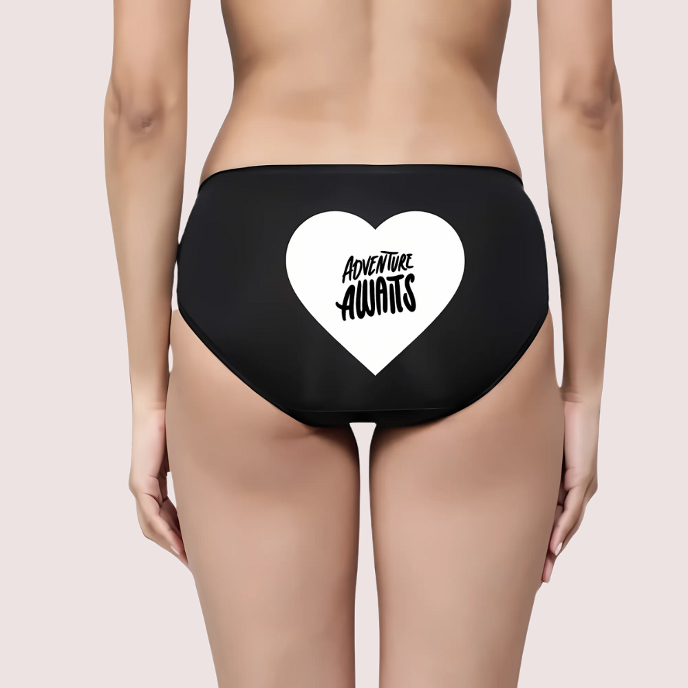 Black Panty with a white heart and 'Adventure Awaits' text on a beige background