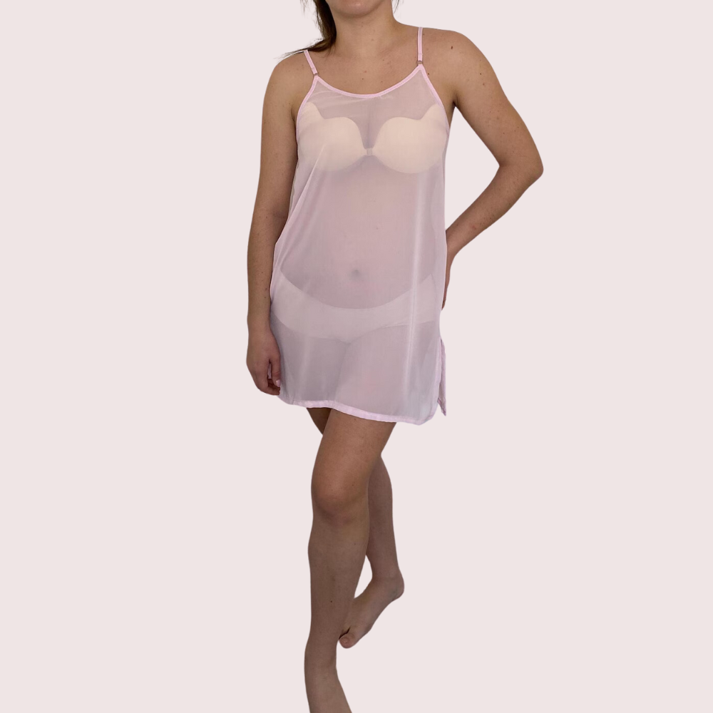 Woman wearing a sheer pink nightgown on a plain background