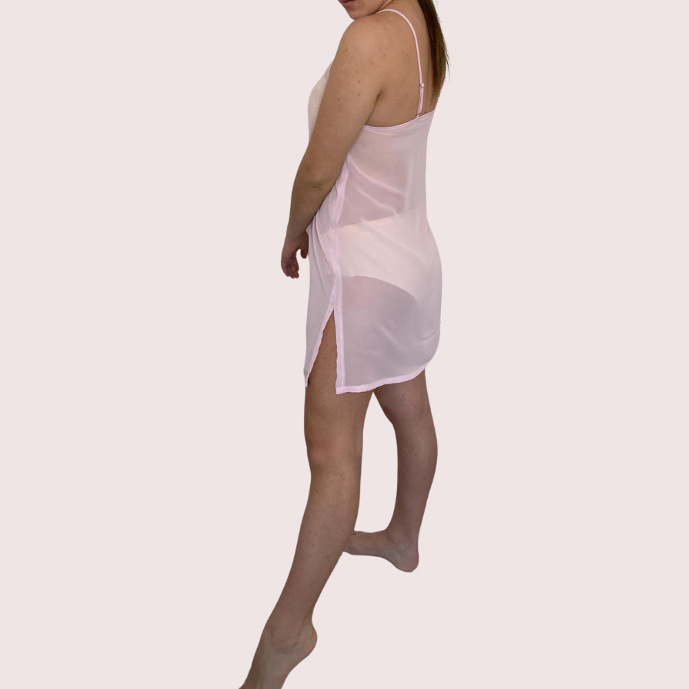 Woman wearing a sheer white slip on a light pink background