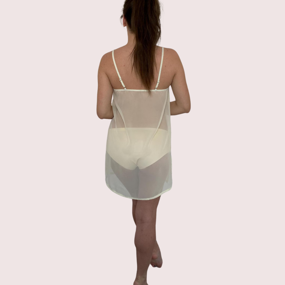 Woman wearing a sheer white nightgown on a light pink background