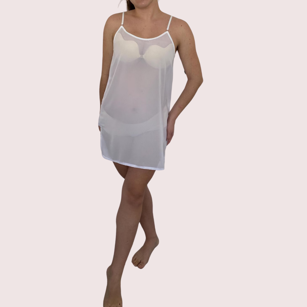 Woman wearing a sheer white nightgown on a plain background