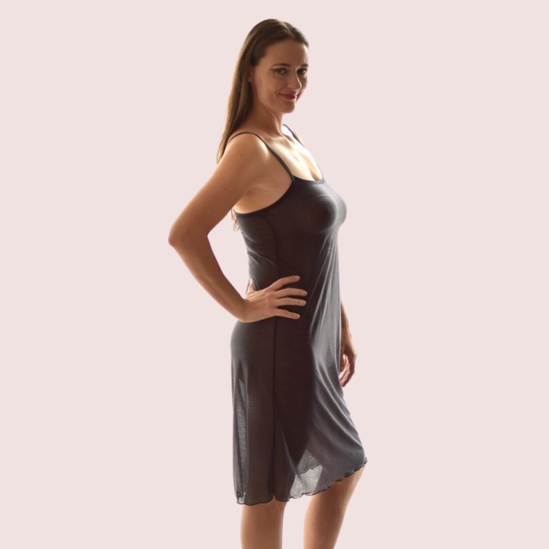 Woman wearing a gray slip dress against a plain background