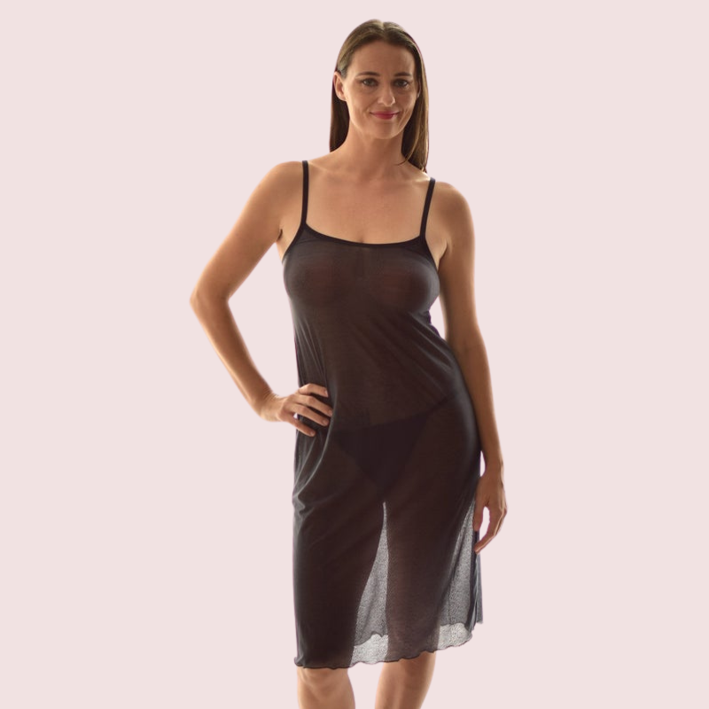 Woman wearing a sheer black slip dress on a light pink background