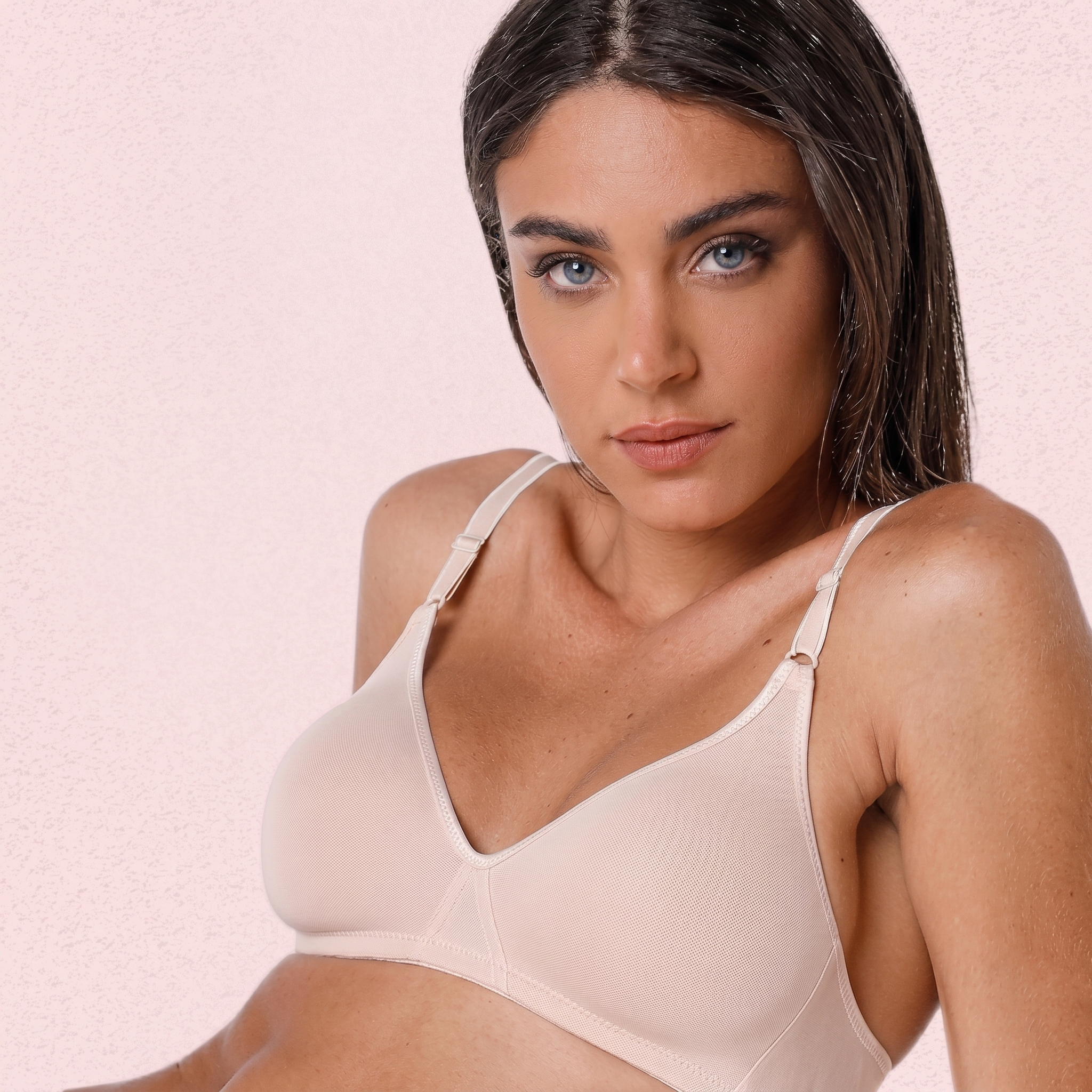 Woman wearing a beige bra against a pink background