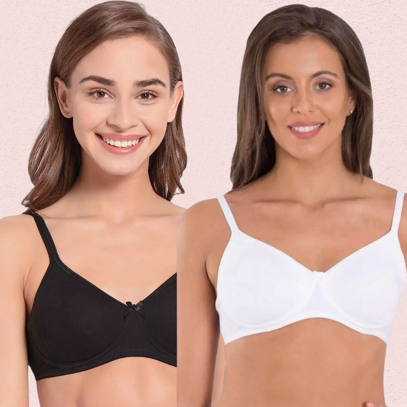 Two women wearing black and white bras against a pink background