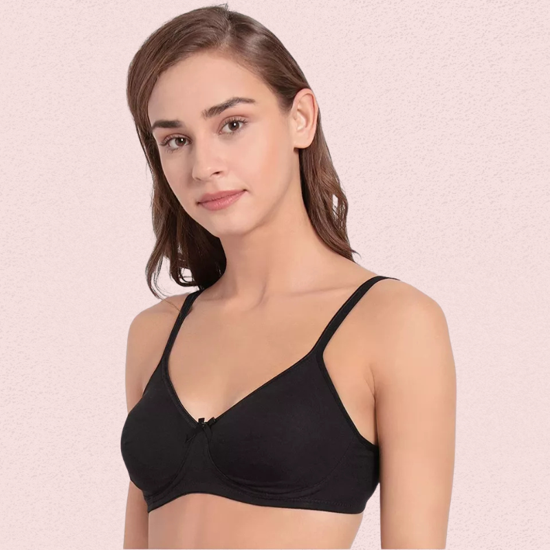 Woman wearing a black bra against a light pink background