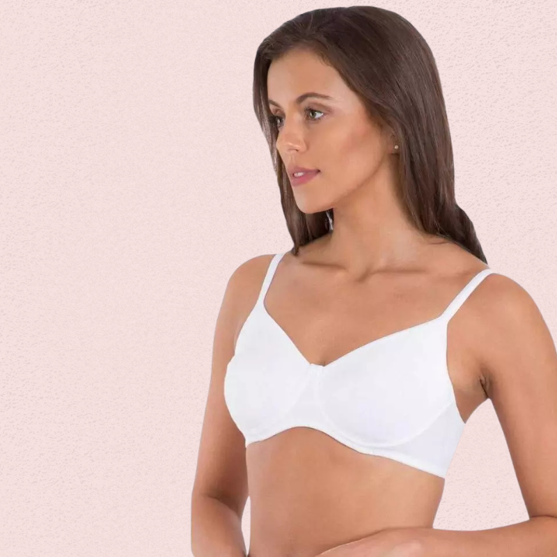 Woman wearing a white bra against a light pink background
