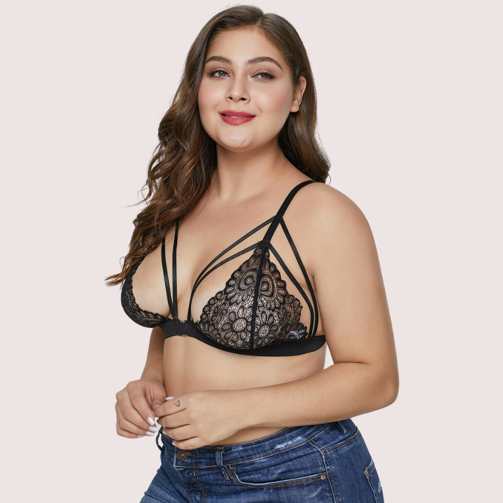 Woman wearing a black lace bralette on a light pink background