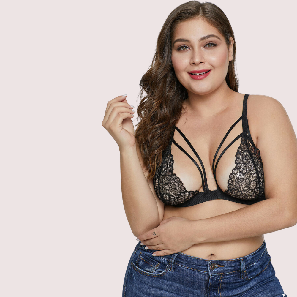 Woman wearing a black lace bralette with straps on a light pink background