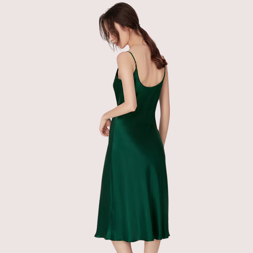 Woman wearing a green slip dress on a light pink background