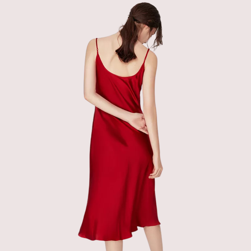 Woman wearing a red slip dress on a light pink background