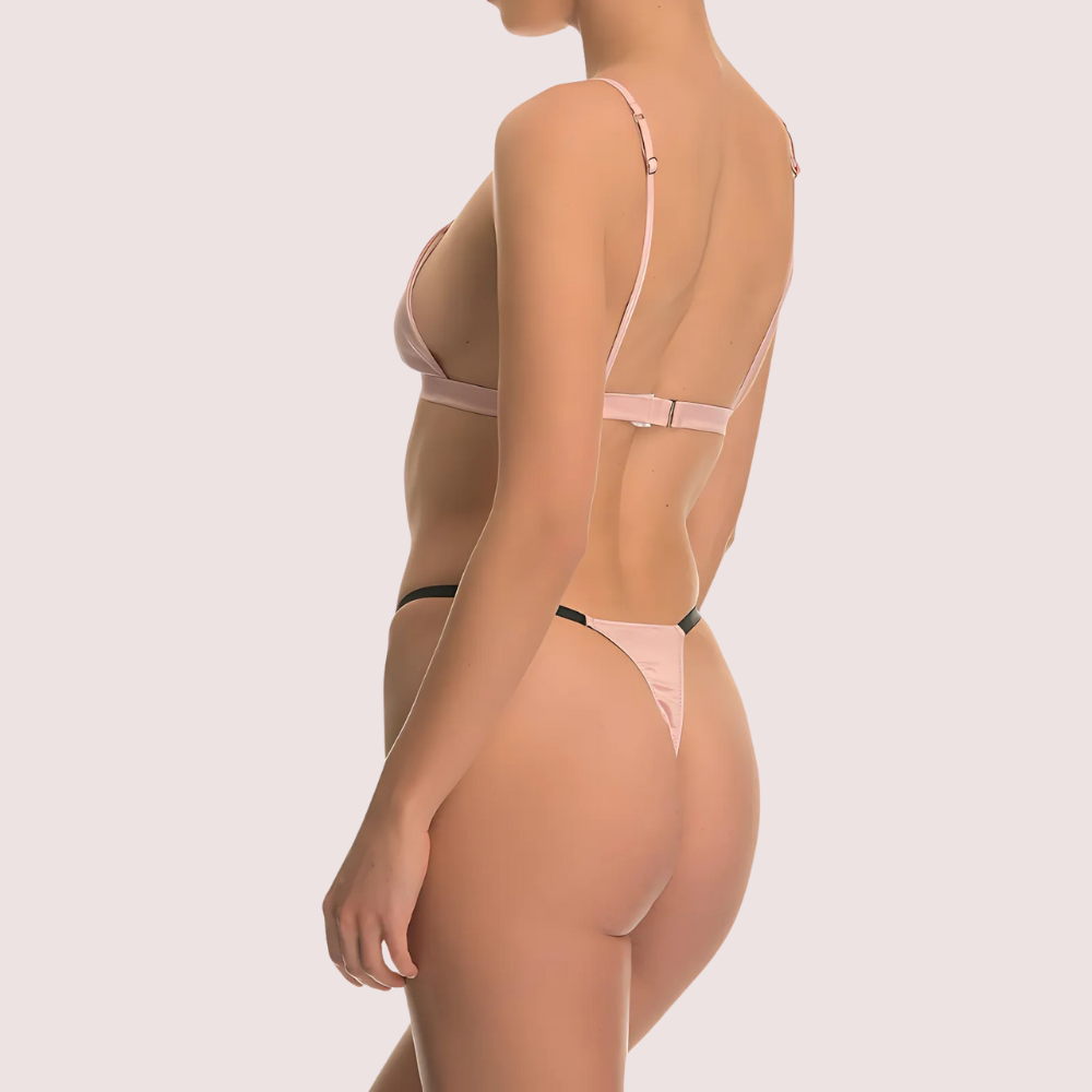 Woman wearing a sheer pink lingerie set on a light gray background