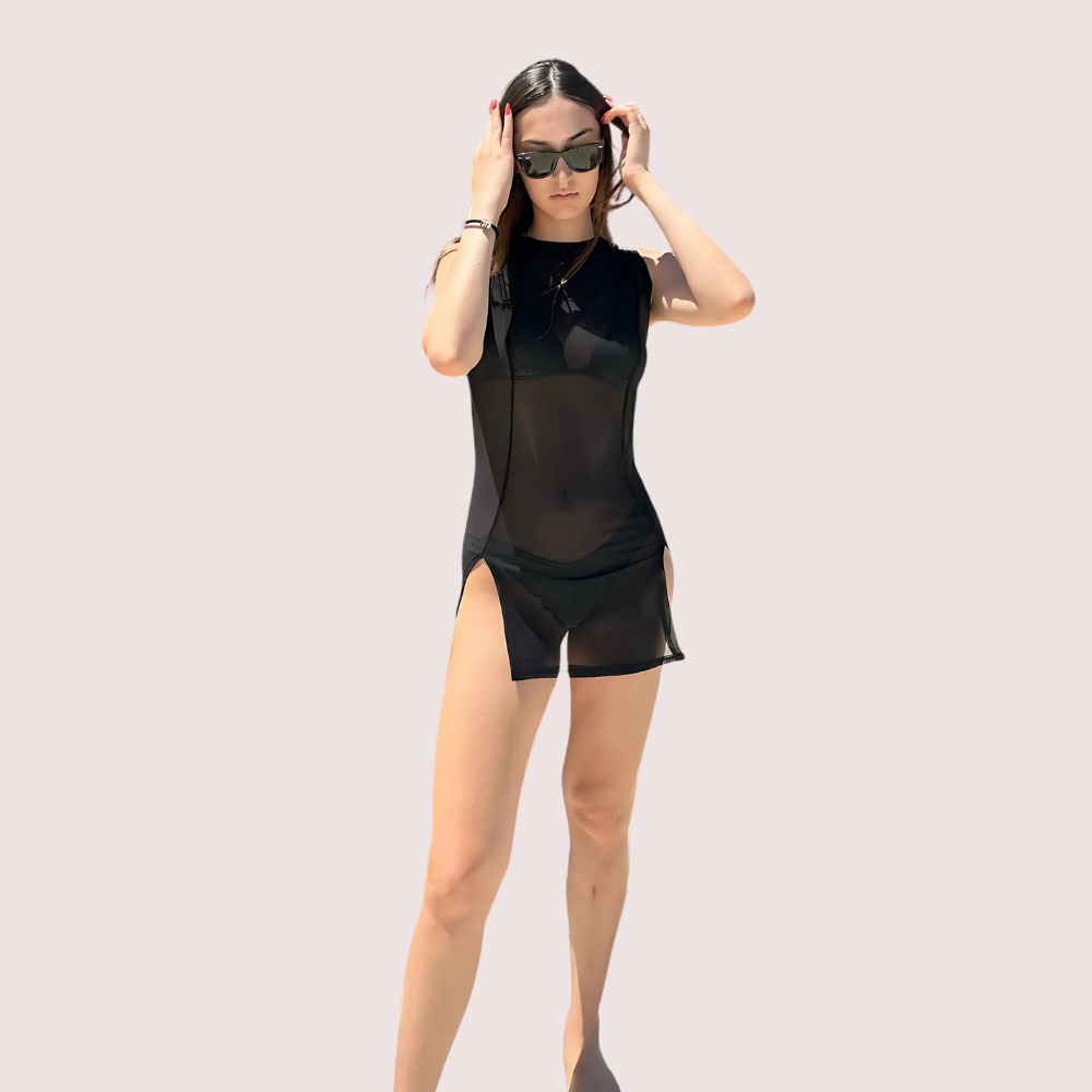 Woman wearing a black sheer outfit with sunglasses on a light pink background