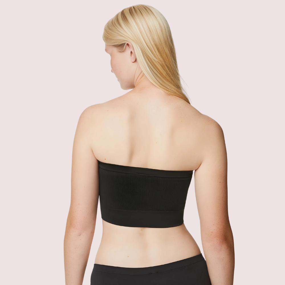 Woman wearing a black strapless top against a light pink background