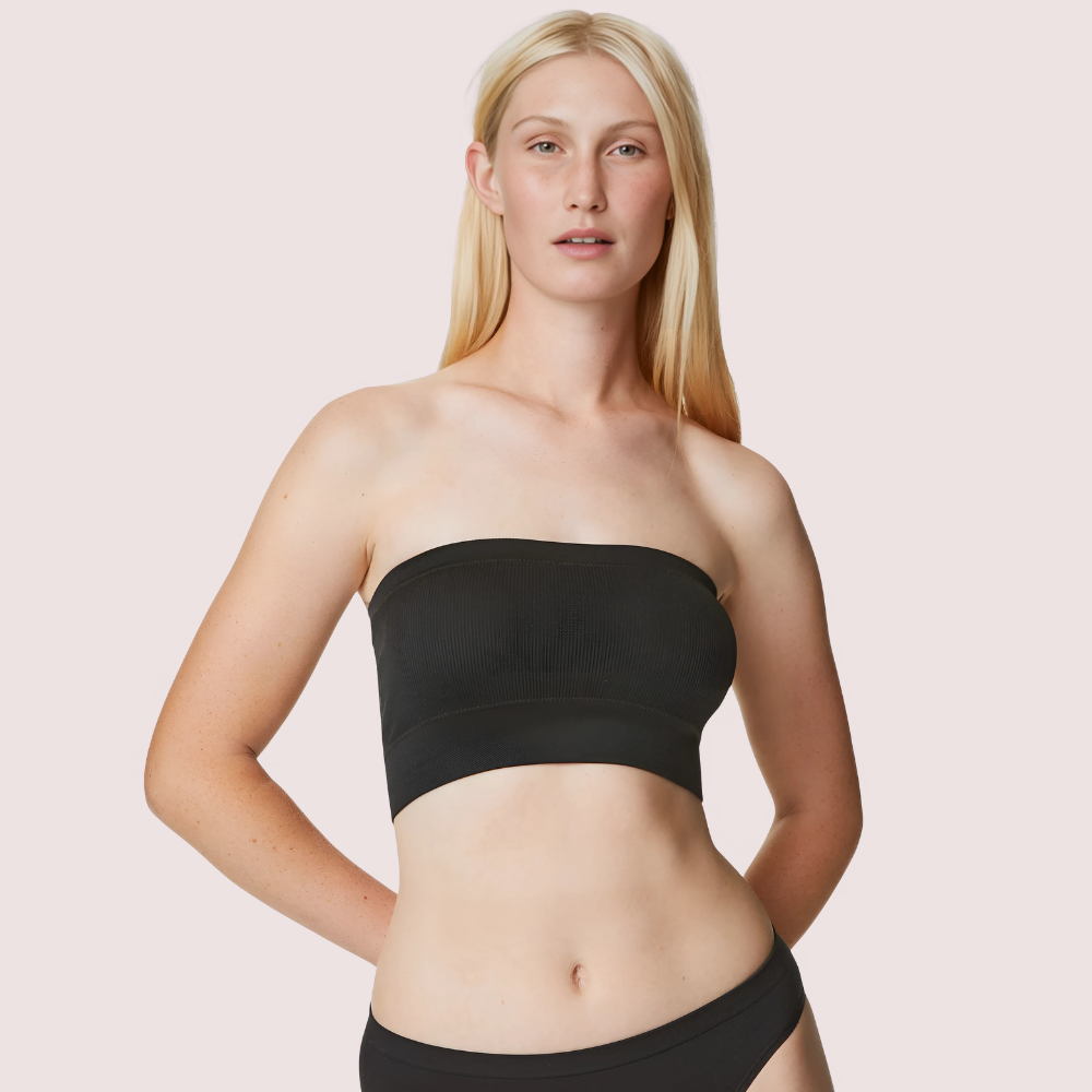Woman wearing a black strapless top against a light pink background