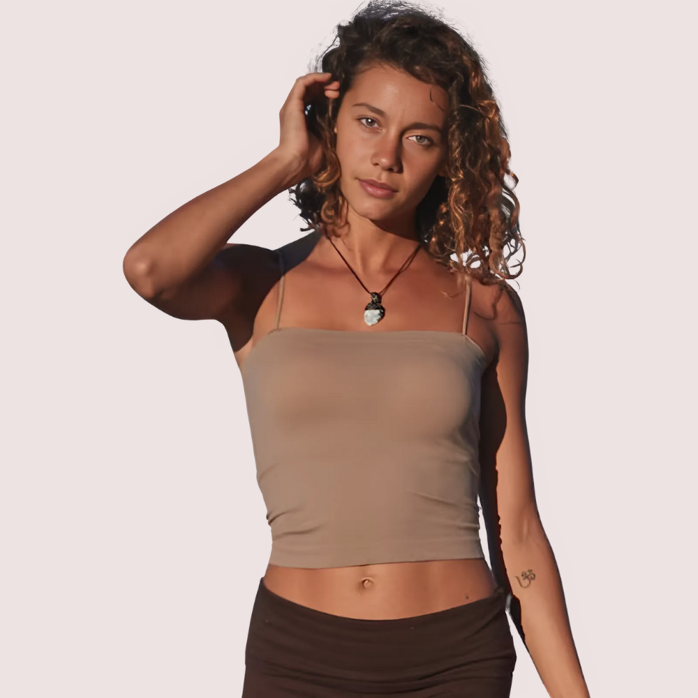 Woman wearing a beige tank top and brown skirt against a plain background