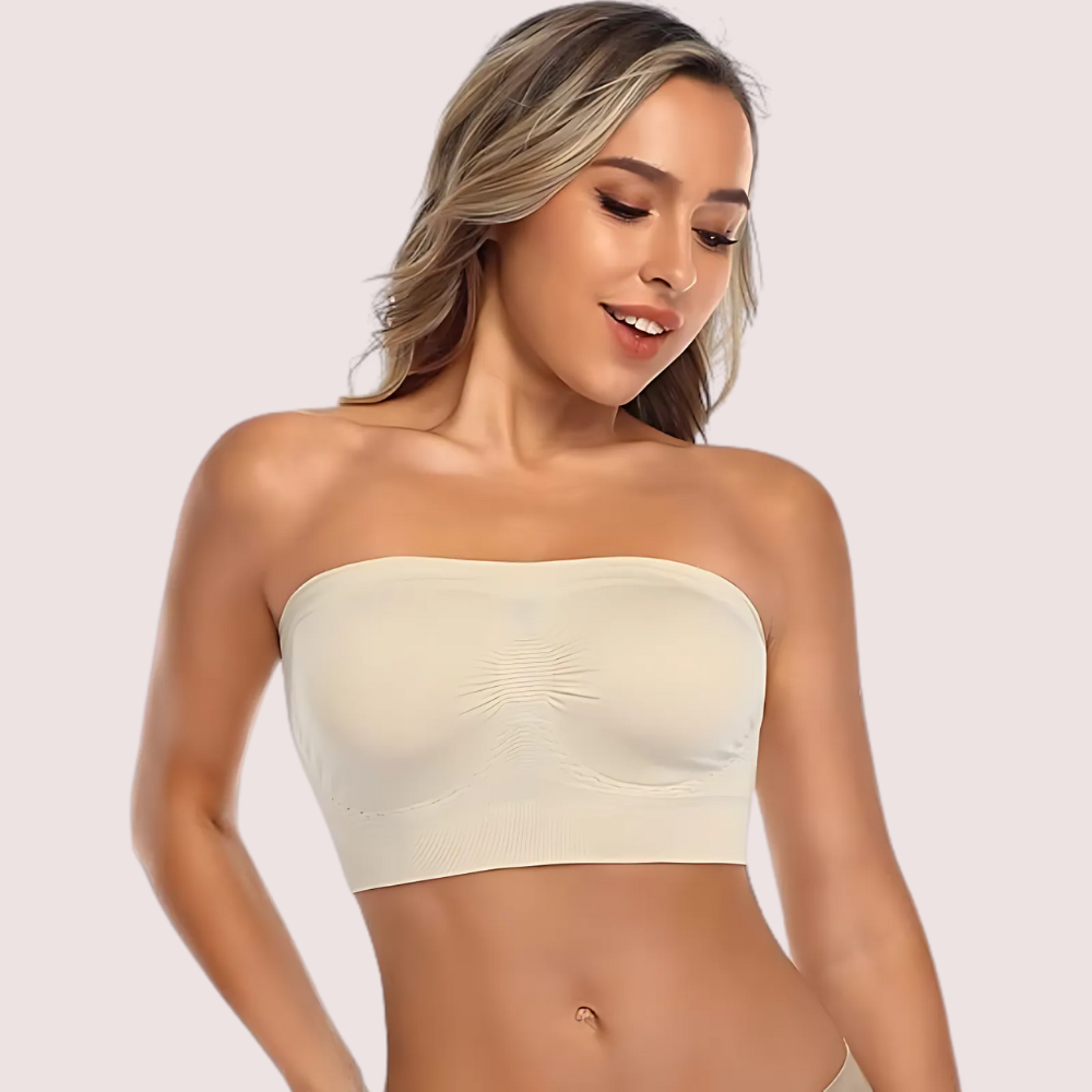 Woman wearing a beige strapless top against a plain background